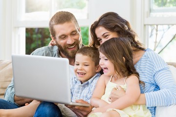 Obraz premium Parents and kids using laptop in living room