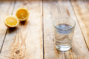 glass of fresh water with halved lemon on wooden table