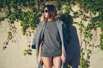 young attractive girl wearing a gray blank t-shirt and coat thrown over her shoulders posing on a...