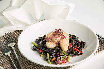 Black squid ink pasta is paired with scallops