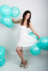 Fototapeta premium beautiful curly girl in a white dress and sunglasses in the style of disco playing with balloons