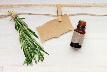 Fresh rosemary twigs and bottle essential oil, empty parchment label.