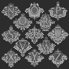 Set of heraldic monograms in coats of arms form. White floral decorative stamps of letters from N to Z. Isolated tattoo labels in vintage baroque style.