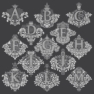 Set of heraldic monograms in coats of arms form. White floral decorative stamps of letters from A to M. Isolated tattoo labels in vintage baroque style.