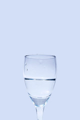 Close up water in wine glass on blue background