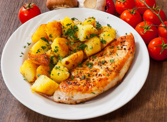 Grilled chicken breast with potato in a plate on wooden table