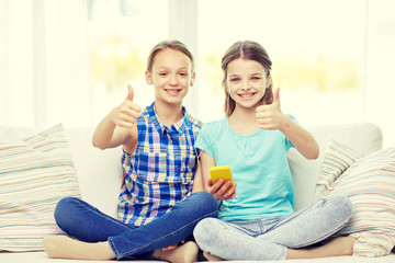 happy girls with smartphone sitting on sofa