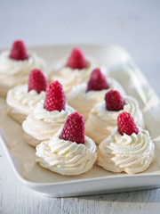 Meringue cakes Pavlova with whipped cream and fresh raspberries