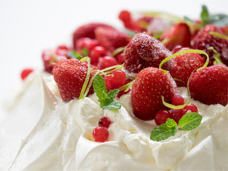 Meringue cake Pavlova with whipped cream, frozen strawberries and red currants