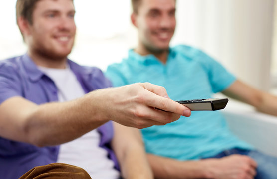happy male friends with remote watching tv at home