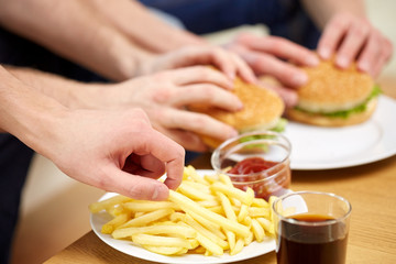 close up of male hands with fast food on table