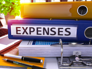 Obraz premium Blue Ring Binder with Inscription Expenses on Background of Working Table with Office Supplies and Laptop. Expenses - Toned Illustration. Expenses Business Concept on Blurred Background. 3D Render.