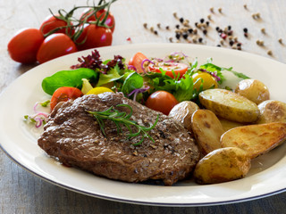 Roasted beef steak with baked potatoes and vegetable salad 