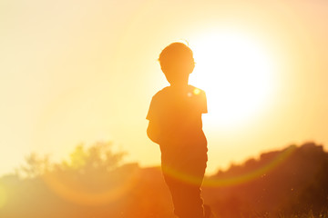 silhouette of little boy running at sunset