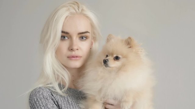 Cinemagraph Beautiful Blonde Woman With Her Spitz Isolated On Grey