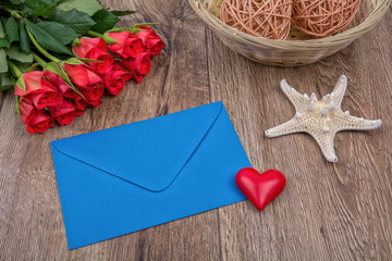 Envelope, roses and starfish on a wooden background
