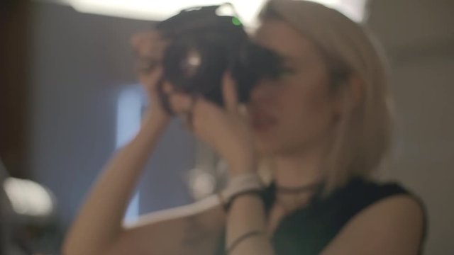 Zooming in of young female photographer taking pictures at studio