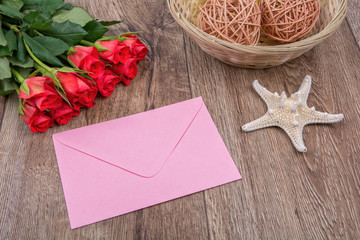 Envelope, starfish and roses on a wooden background