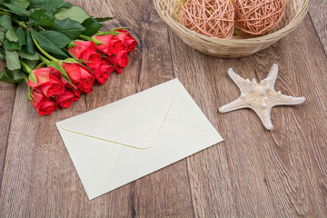 Envelope, starfish and roses on a wooden background