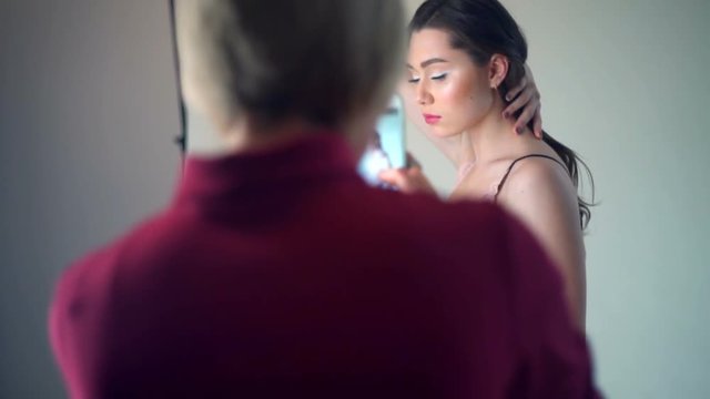 woman takes a picture of a posing model in studio by smartphone