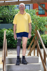 Senior leg amputee standing on staircase of training course for