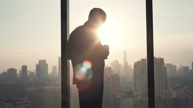 Businessman fasten his shirt standing by window in office 
