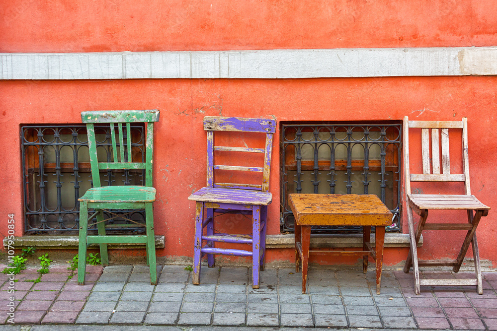 Wall mural Three old multi-colored chairs stand near a pink wall, Istanbul