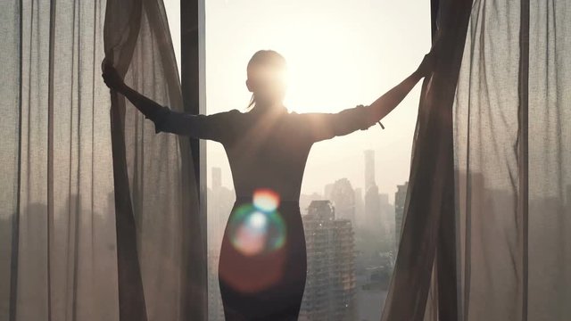 Young businesswoman unveil curtain and looking out of window
