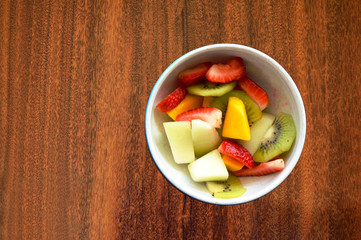Bowl with tropical fruits on a wood table