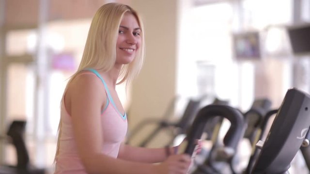 Girl smiling to camera during workout on orbitrek