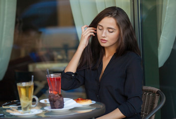 pretty young woman sitting in cafe with a cup of tea or coffee outdoor. Charming woman in a restaurant. Woman with coffee and cake. Woman portrait indoors.