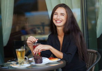 pretty young woman sitting in cafe with a cup of tea or coffee outdoor. Charming woman in a restaurant. Woman with coffee and cake. Woman portrait indoors.