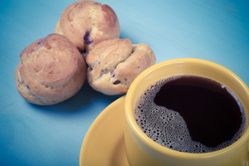 Fresh homemade profiteroles and cup of coffee on blue wooden tab