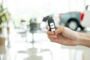 Human hands giving thumbs up with car key in car shoowroom