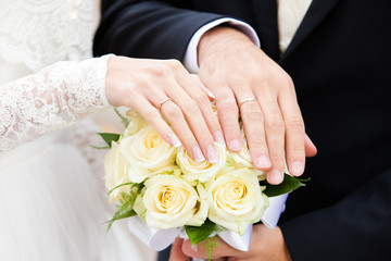 Obraz na płótnie Canvas hands of groom and the bride on a yellow bouquet