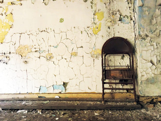 Rusty old abandoned chair propped up against wall - landscape color photo