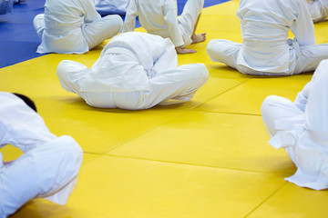 People in kimono warming up on tatami on martial arts training seminar. Selective focus