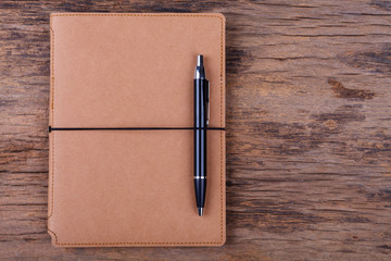 Blank note pad with pen on wood background