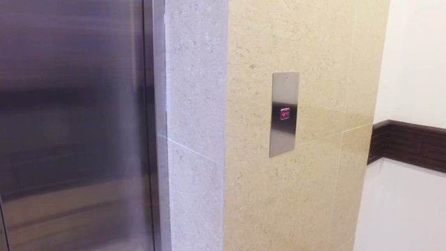 woman's hand pushes the elevator button
