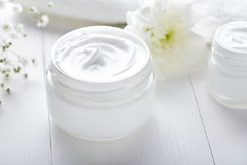 Poster Anti wrinkle cosmetic cream with herbal flowers face, skin and body care hygiene moisture lotion wellness therapy mask in glass jar with towel on white background © GreenArt Photography