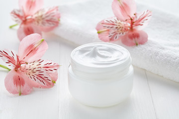 Fototapeta na wymiar Yogurt cream natural organic beauty cosmetic product wellness and relaxation makeup mask in glass jar with pink flowers and towel on white background