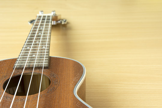 Close up of wooden ukulele on wooden background