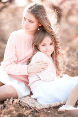 Two young girls sitting in field outdoors. Summer time.