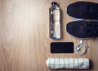 Sport equipment, Sneakers, water, towel, phone and earphones on wooden background, Flat lay