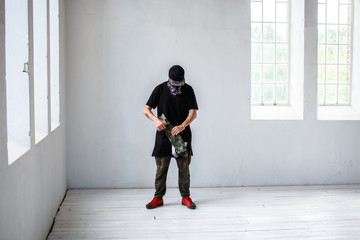 A man in a mask and black clothes holds skateboard.