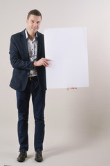 studio shot of a handsome man in a suit holding up a blank white