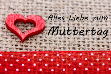 ein Herz liegt auf einem Stoff, dazu ein Text für den Muttertag