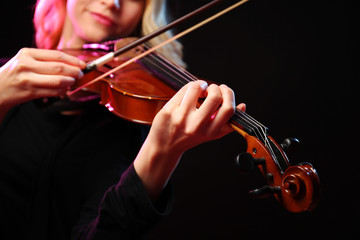 Woman plays violin on black background, close up