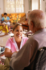 Fototapeta premium Hospice Nurse Listening To Elderly Man On Wheelchair