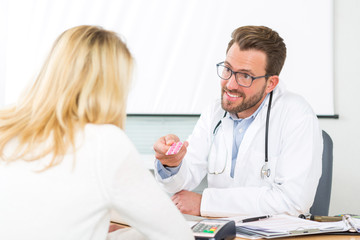 Young attractive doctor giving pills to a patient